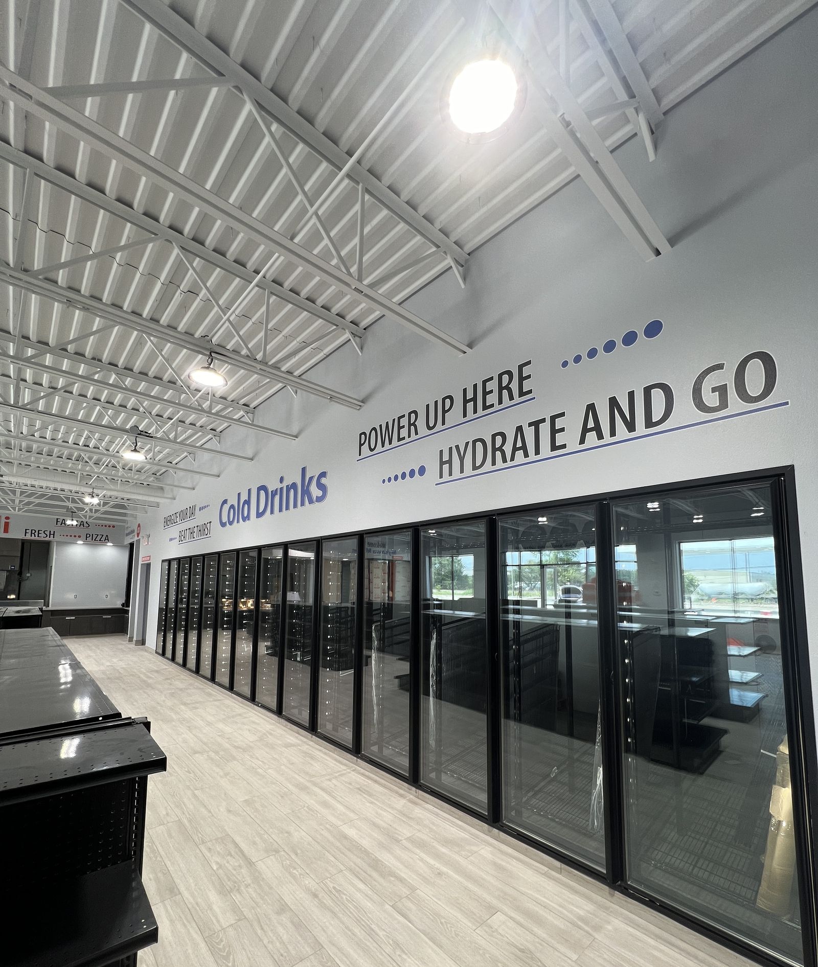 Interior wayfinding and wall graphics across a convenience store cooler wall
