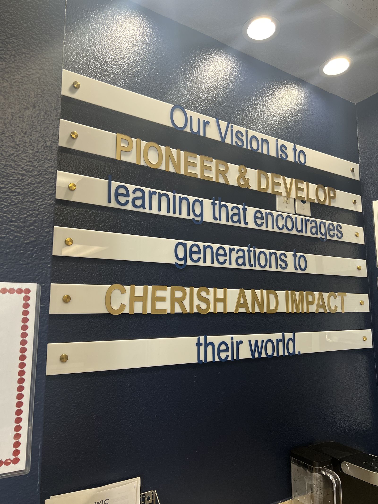 Dimensional vision statement lettering on a navy office wall